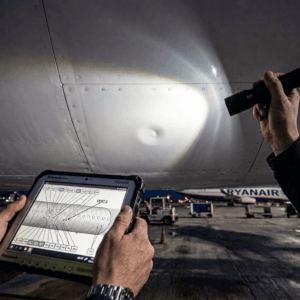 Engineer records aircraft structural damage on a fuselage dent at night